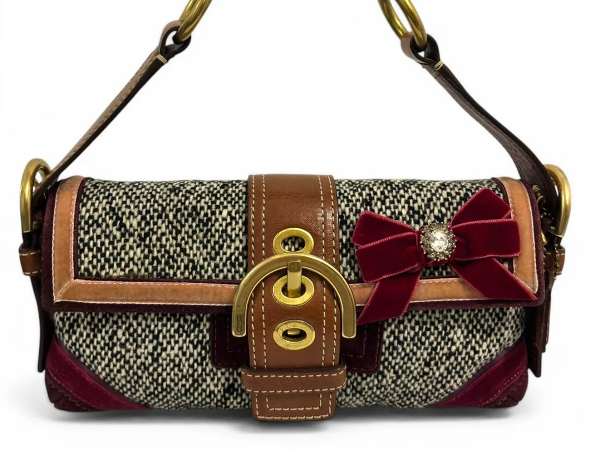 Vintage Coach shoulder bag with black-and-cream woven panels, brown leather trim, gold-tone buckle hardware and a burgundy bow with a jewelled centre.